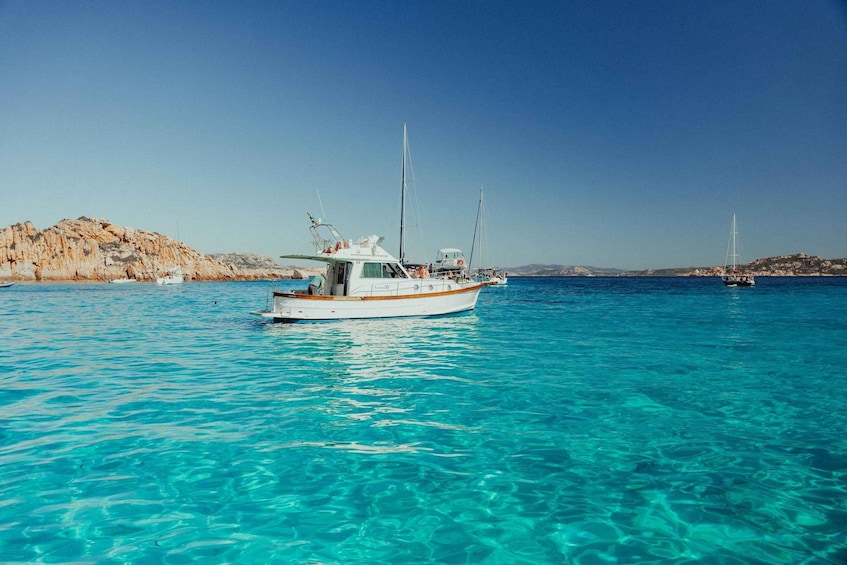 A boat on clear turquoise water with rocky hills in the background. 4