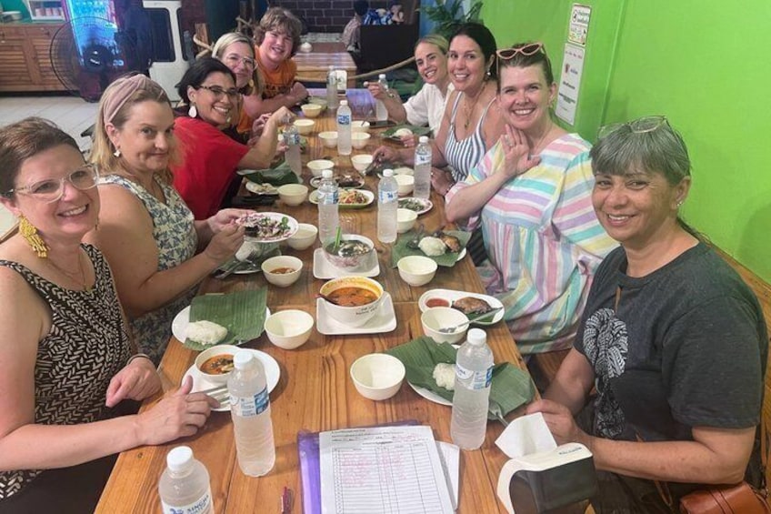 A group of people sitting around a table with various dishes and drinks. 4
