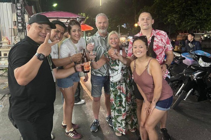 A group of people posing for a photo in an outdoor setting with a motorcycle and a red umbrella in the background. 3