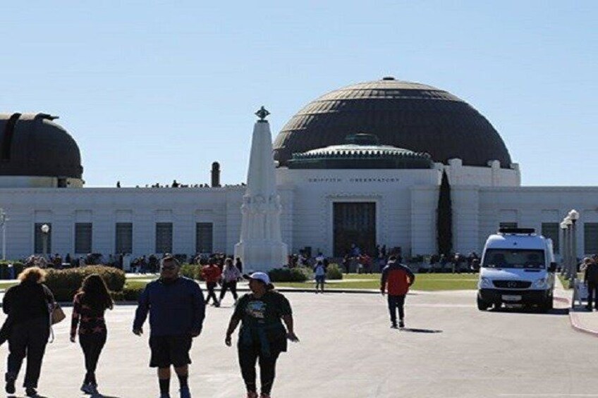 A large building with domes, a statue, and people walking around. 2