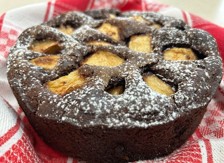 A round cake with a lattice top, dusted with powdered sugar, on a red and white checkered cloth. 4