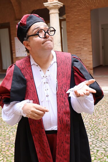 A person in academic regalia pointing with both hands. 2