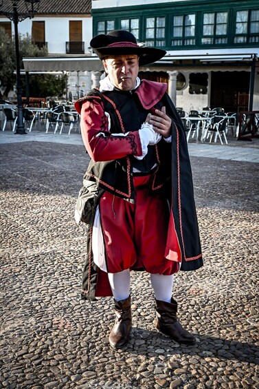 A person in historical costume standing on cobblestone pavement. 2