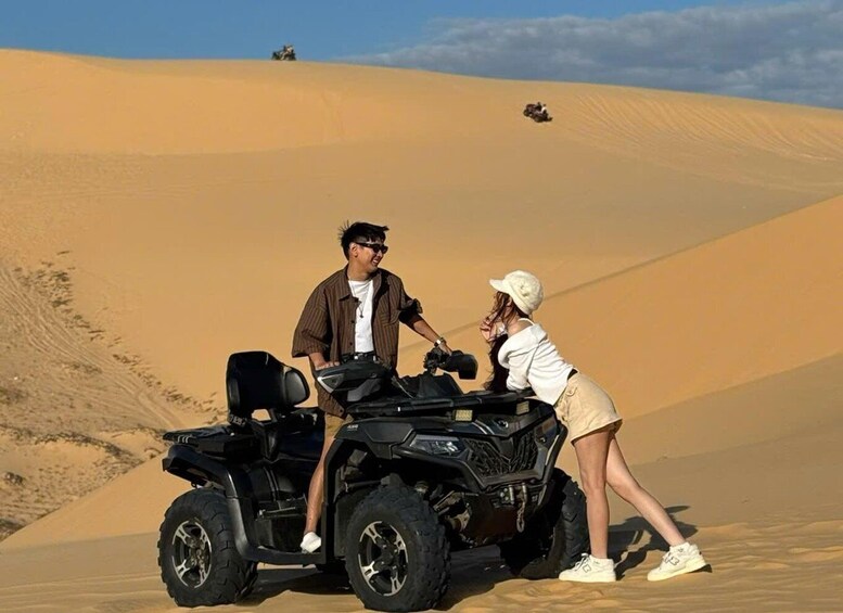 A person on a quad bike in a desert with sand dunes in the background. 5