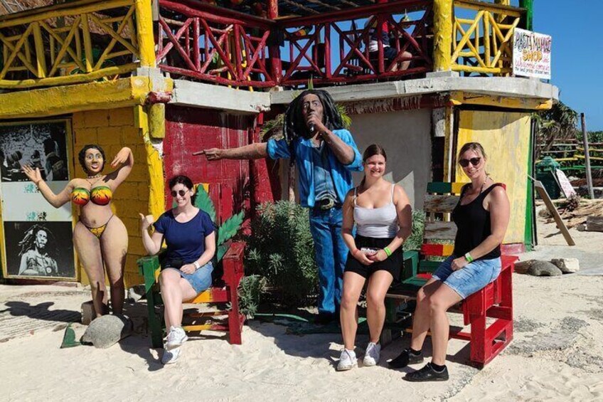 A group of people sitting and standing in front of a colorful building with a sign that reads 'PAPAYA MANAGER.' 3