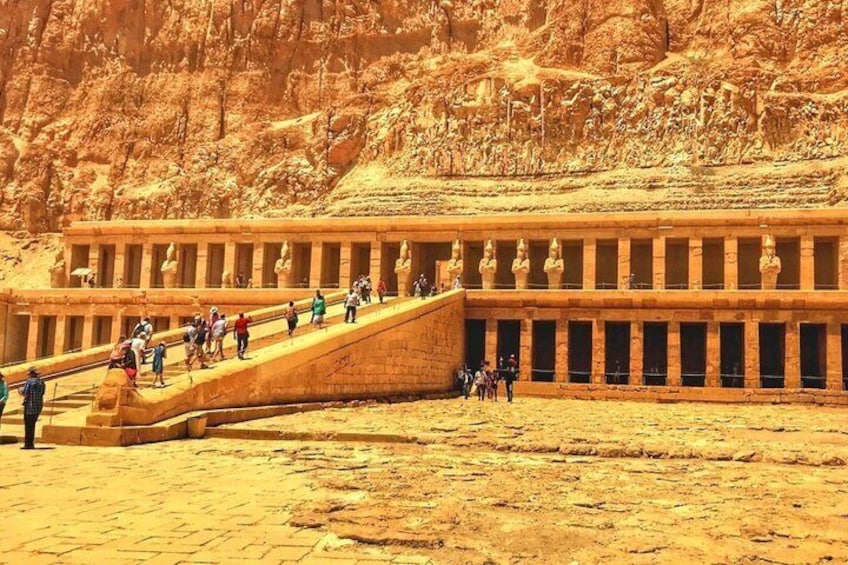 A large ancient Egyptian temple with a long staircase leading up to it, surrounded by desert. 1
