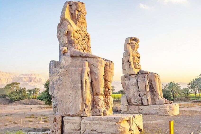 Ancient stone statues in a desert landscape with mountains in the background. 4