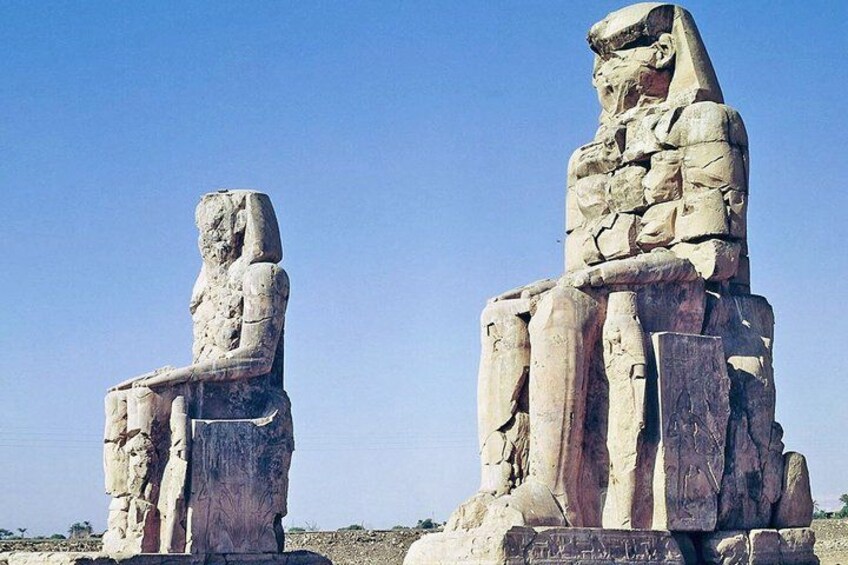 Two large stone statues of seated figures, one with a lion head, set against a clear sky. 4