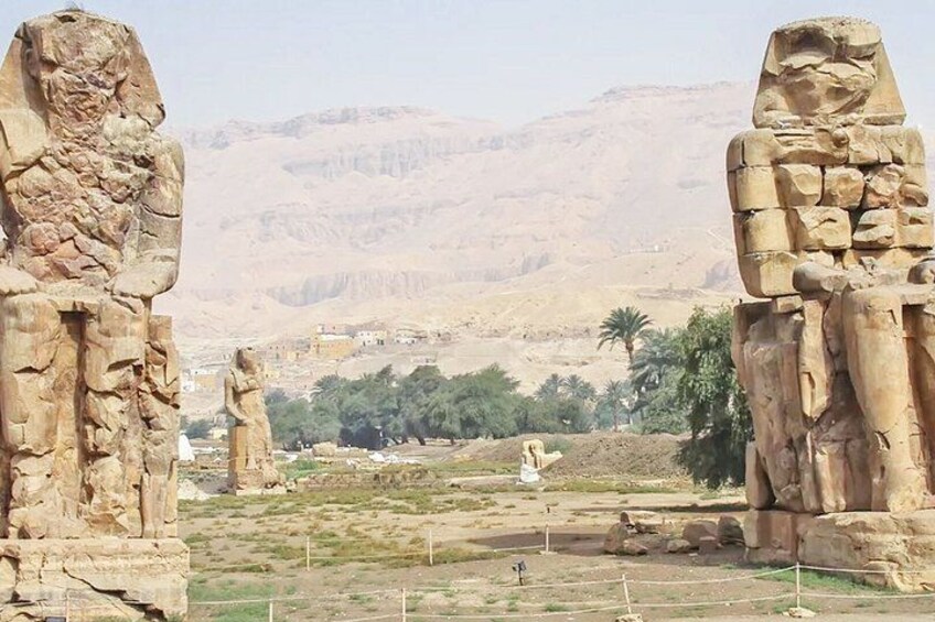Ancient stone statues in a desert landscape with mountains in the background. 5