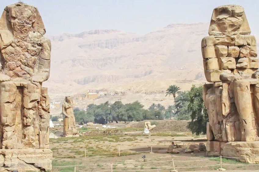 Ancient stone statues in a desert landscape with mountains in the background. 5