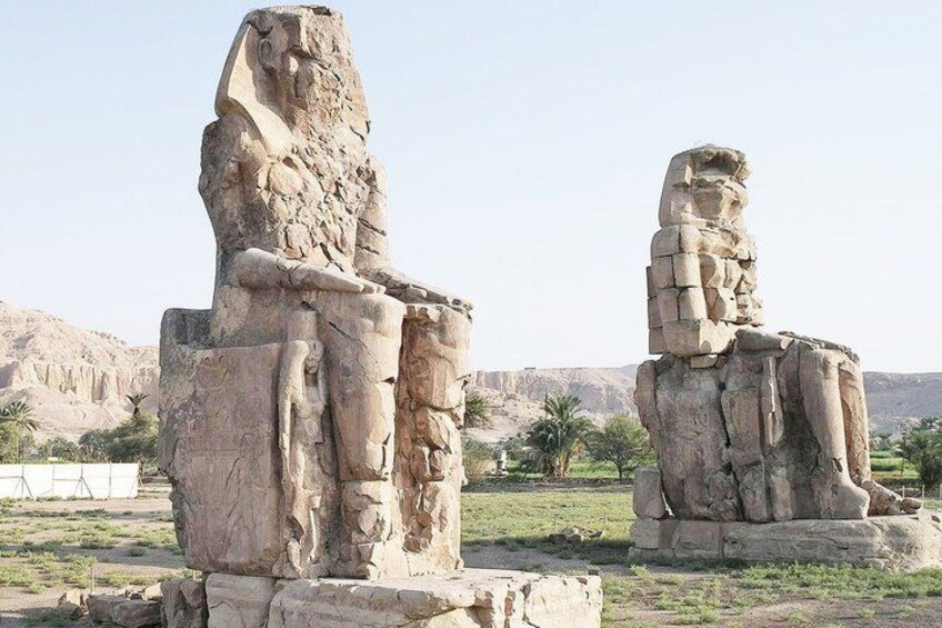 Two large stone statues in an open area with a desert landscape in the background. 2