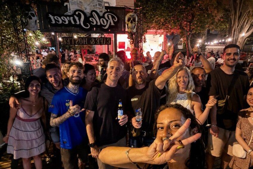 A group of people gathered outside a venue with a sign that reads 'Tropical Nightclub.' 1