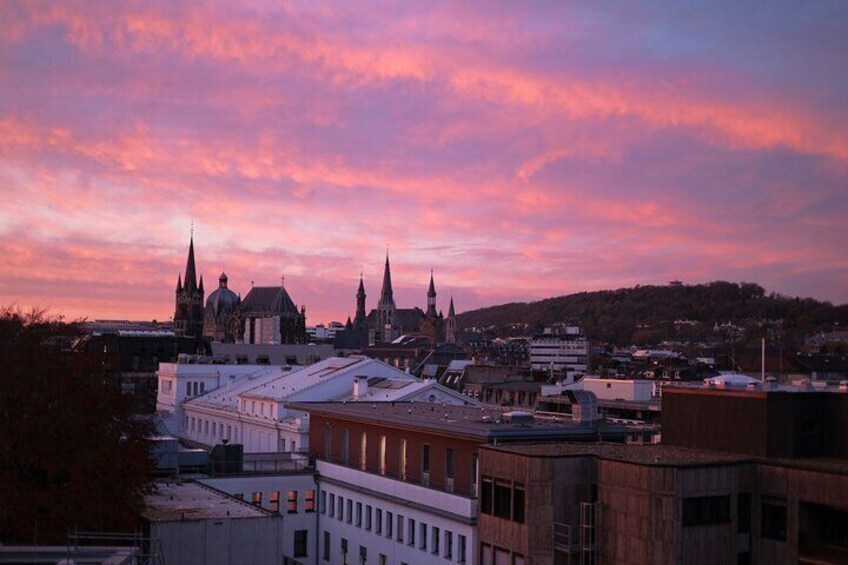 A cityscape with a prominent church and spires, surrounded by buildings and a sunset sky. 4