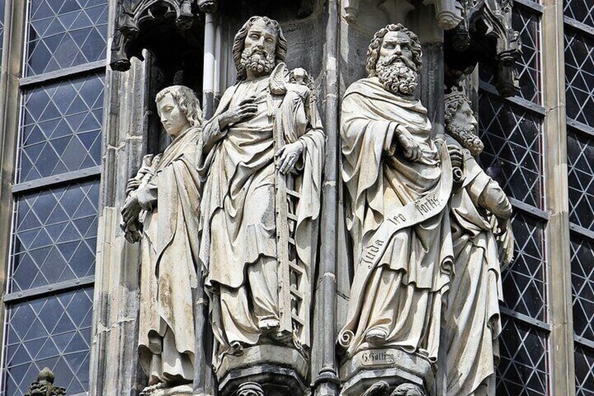 A stone facade with three statues of robed figures, each with a distinct posture and expression. 3