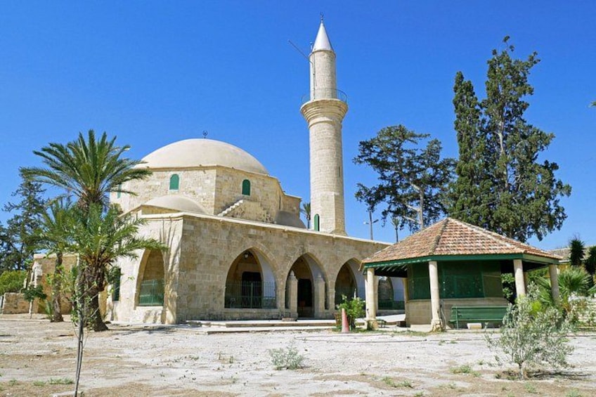 A mosque with a dome and a minaret, surrounded by palm trees and a clear sky. 4