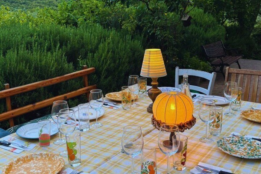 An outdoor dining table set with plates, glasses, and a decorative lamp. 2