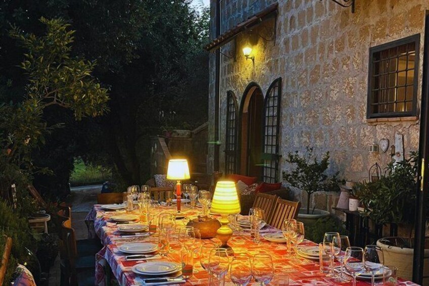 An outdoor dining table set up with candles and plates, surrounded by stone walls and greenery. 3