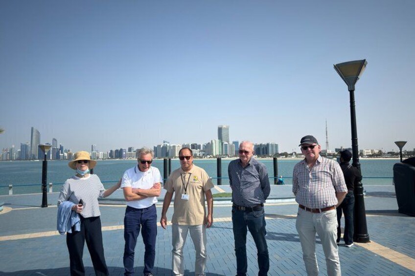 A group of people standing on a waterfront promenade with a city skyline in the background. 4