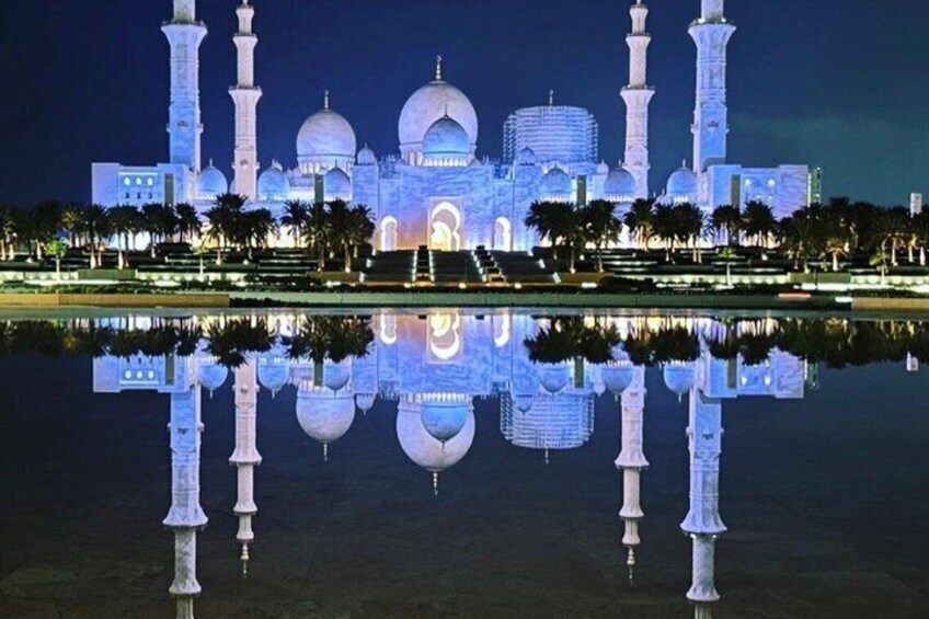 A grand mosque with multiple domes and minarets, reflected in a calm body of water. 3