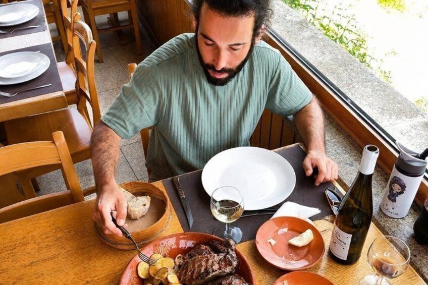 A person dining at an outdoor table with a meal, wine, and a bottle. 3