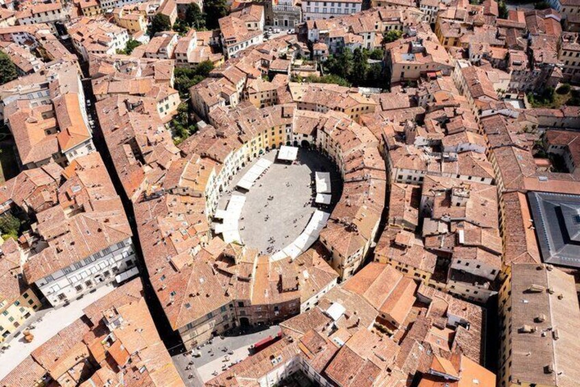 An aerial view of a historic city center with a prominent circular plaza surrounded by traditional buildings. 1