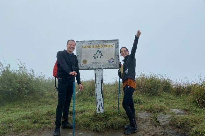 Two people standing next to a signpost with 'LANG BIANG PEAK' written on it. 3