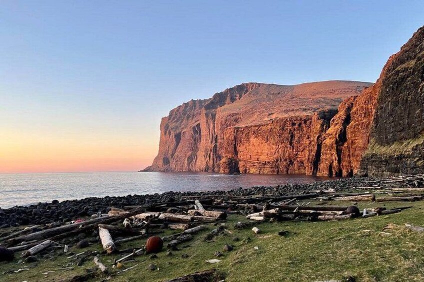 A coastal landscape with cliffs, a rocky beach, and a calm sea. 2
