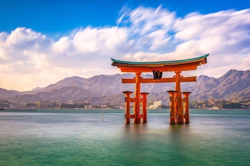 A traditional Japanese torii gate in the water with mountains in the background. 1