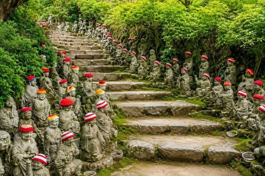 A stone staircase with numerous statues of figures wearing red hats, surrounded by lush greenery. 4
