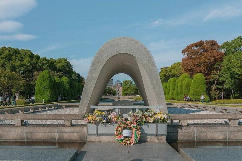 A stone arch monument with a floral wreath in a park. 2