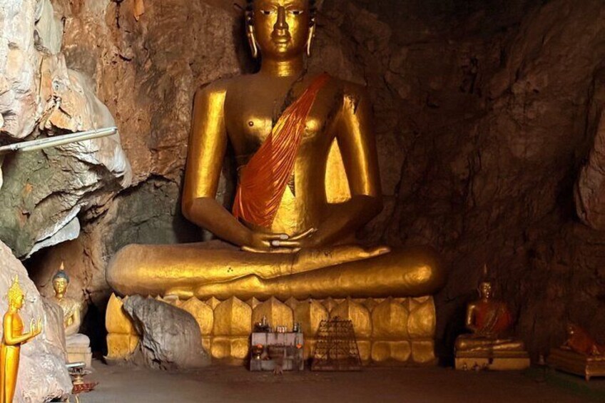 A large golden Buddha statue in a cave with a rocky backdrop. 5