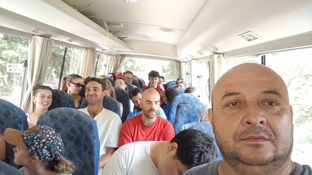A crowded bus interior with passengers seated and standing. 3