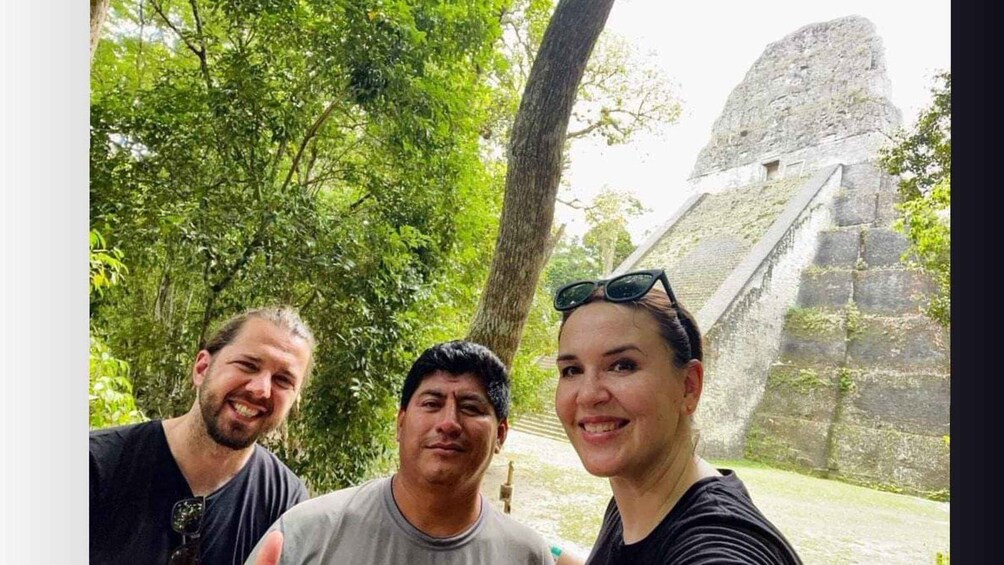 Three people in front of a large stone structure with a pyramid in the background. 4