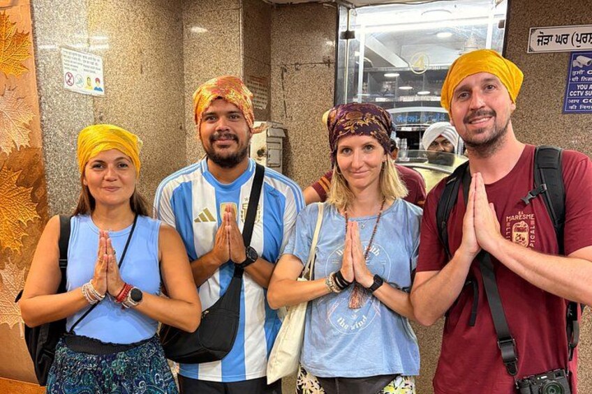 Four people in a prayer position, a wall with a sign, and a counter with items. 4