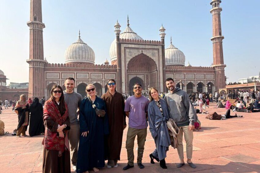 A group of people standing in front of a large, historic building with domes and minarets. 4