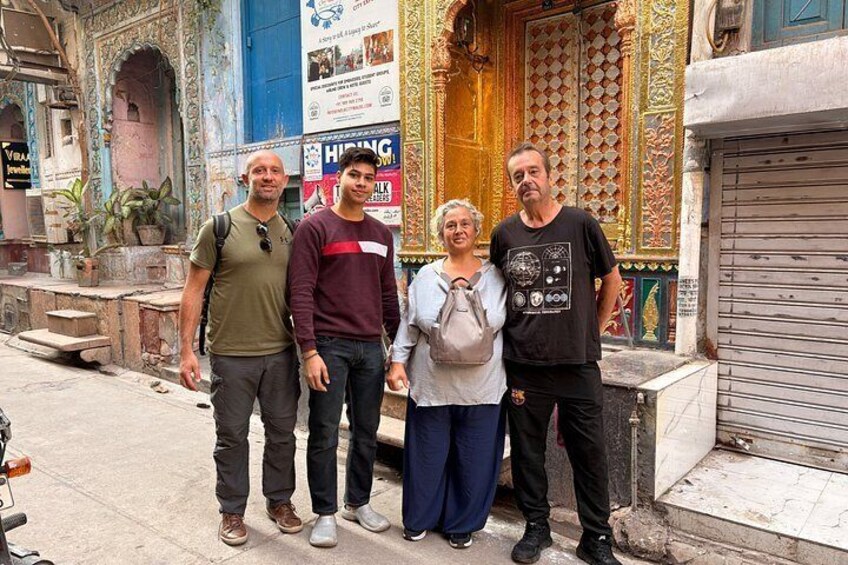 A group of people standing in front of a building with ornate decorations and a closed shutter. 5
