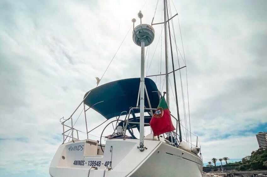 A sailboat with the name '4WIND' and the number '138948' on its bow, a blue canopy, and a red and green flag. 3