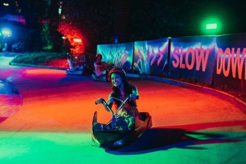 A person on a ride at an amusement park with a 'SLOW DOWN' sign. 3