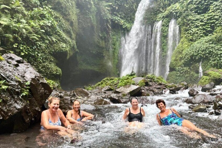 Four people in a natural setting with a waterfall and rocky terrain. 1