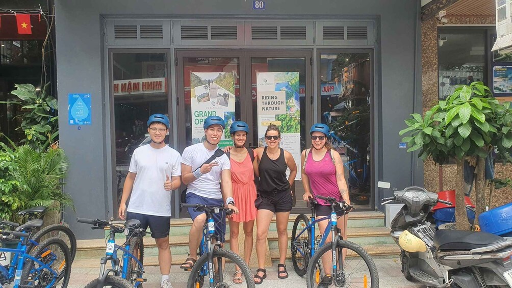 A group of people on bicycles in front of a building with a sign that reads 'Riding Through Nature.' 4