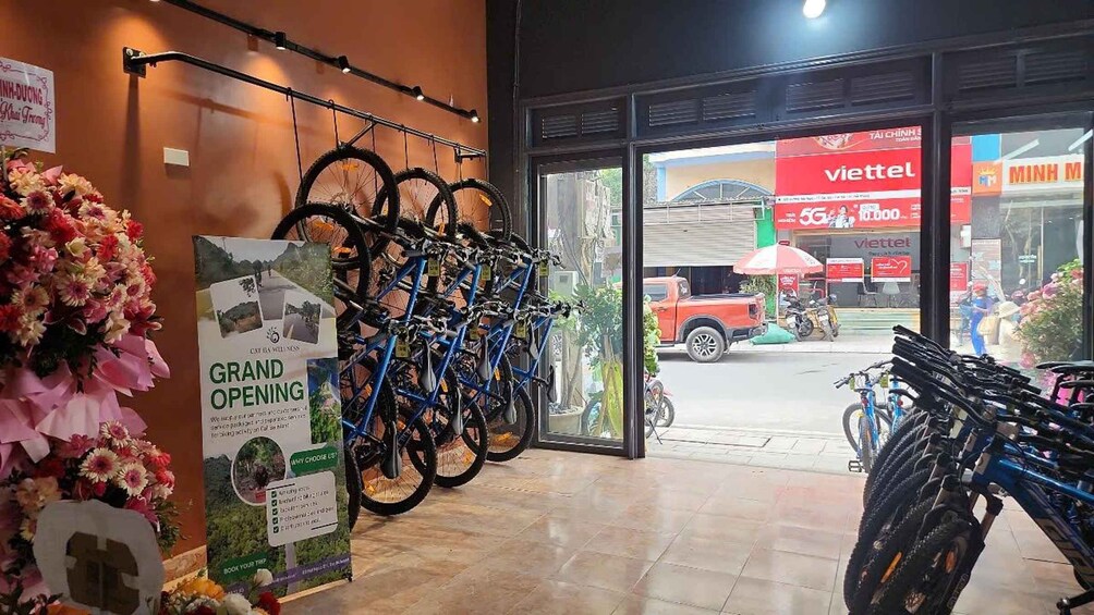 A bicycle shop with a rack of bikes and a sign for a grand opening. 1