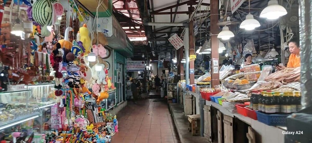 A bustling indoor market with various stalls selling toys, snacks, and other goods. 2