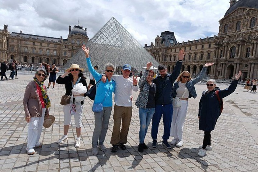 A group of people posing in front of the Louvre Pyramid in Paris. 2