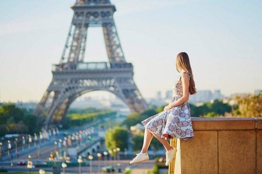 A person sitting on a ledge with the Eiffel Tower in the background. 5