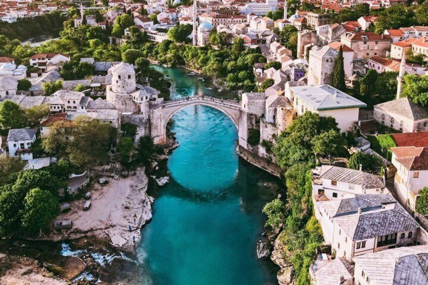 A coastal town with a historic bridge, buildings, and a turquoise river. 1