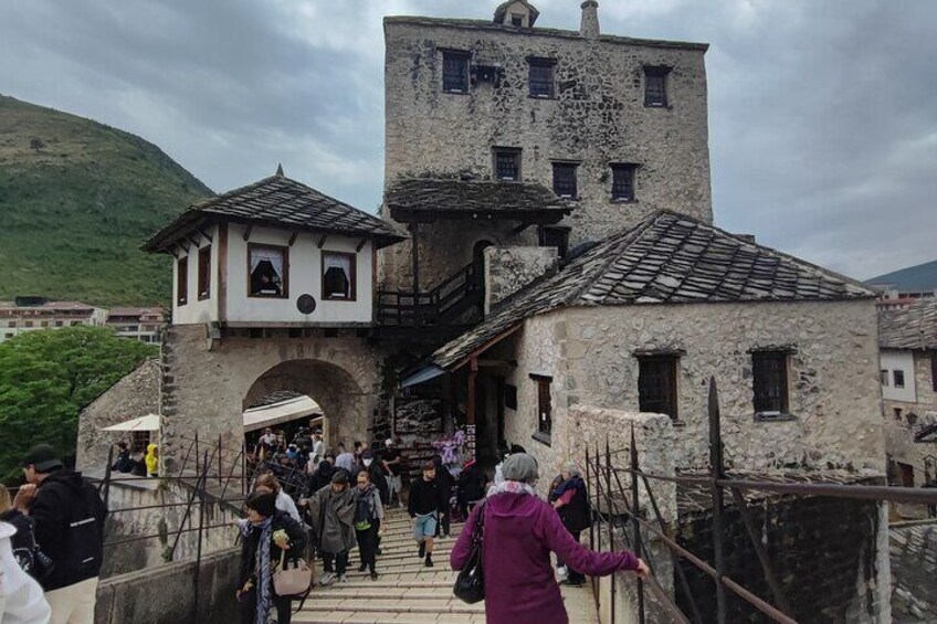 A stone bridge leading to a historic building with a tower, surrounded by lush greenery. 5