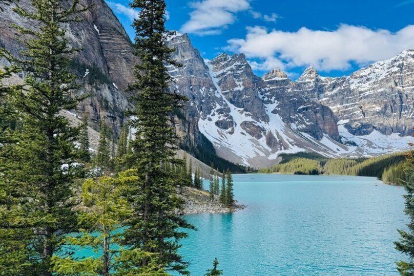 A mountain lake surrounded by trees and snow-capped peaks. 1
