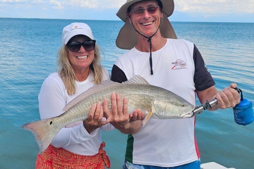Two people holding a fish on a boat with a calm sea in the background. 5