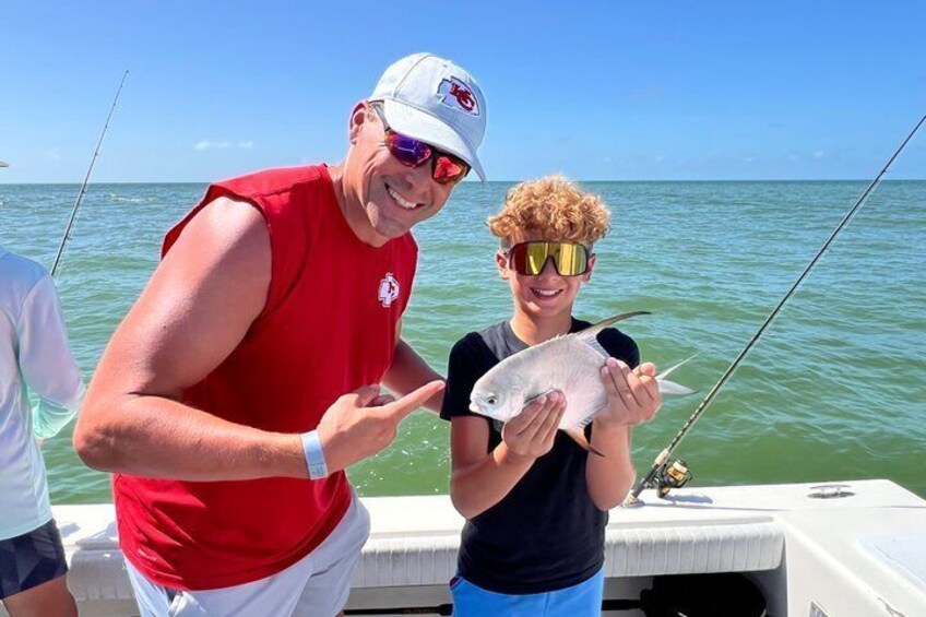 Two people on a boat holding a fish. 2