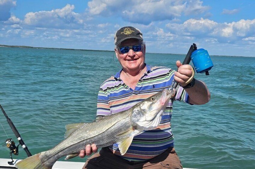 A person holding a large fish on a boat with calm water and a clear sky in the background. 4